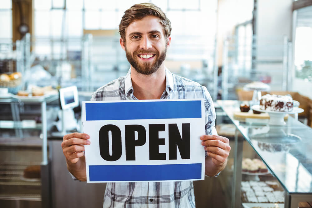 Small business owner holding up open sign