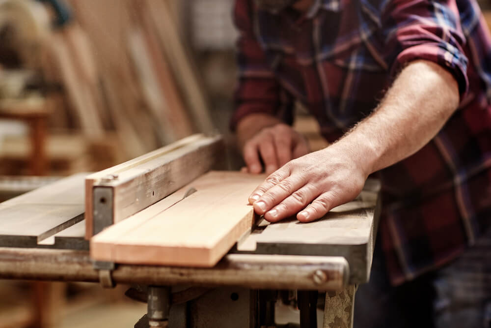 Strong business owner sawing wood